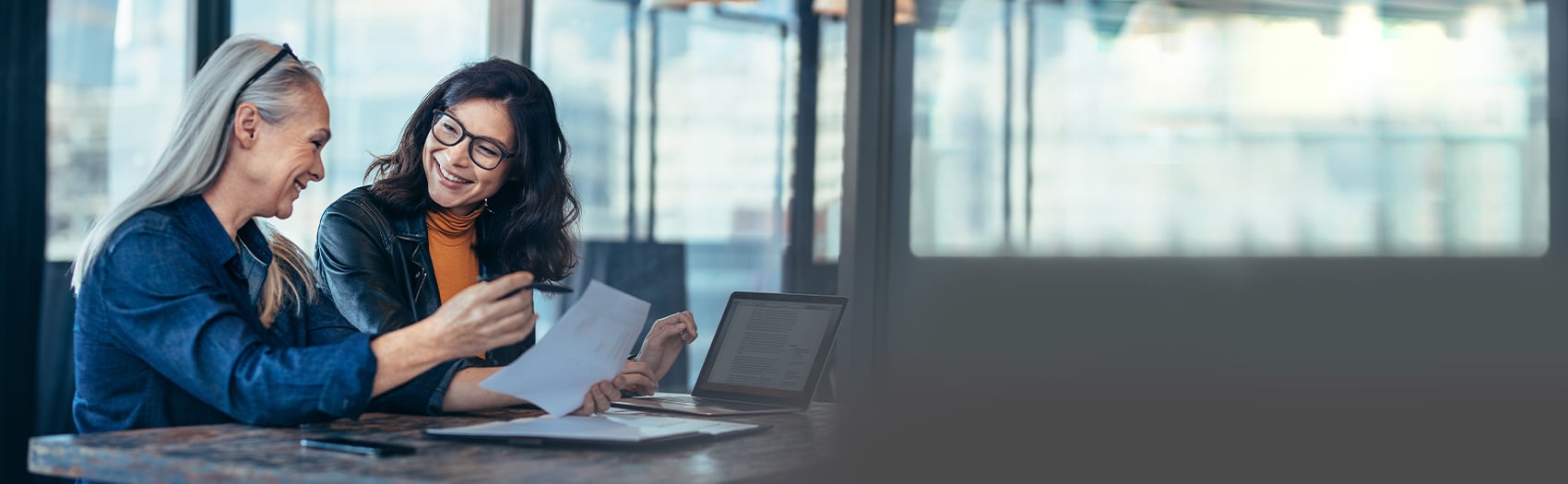 Two women smiling in an offce discussing work stress